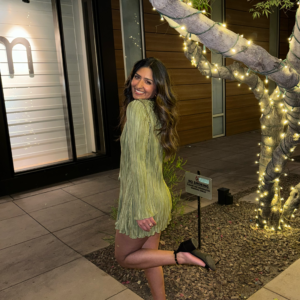 A photo of the founder of Roohm, Manpreet with a green dress, smiling back at the camera